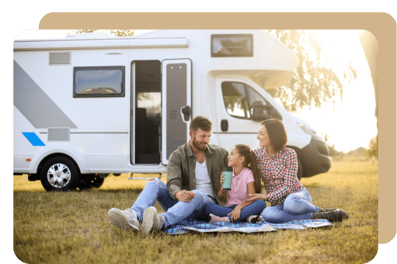 A family happily seating outside with RV parked behind them.